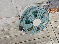 View of the reel spool showing the green hose tightly wound and the large segments of the reel wheel.