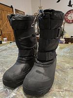 Front and side view of pair of black waterproof men's winter boots showing height and adjustable straps