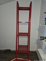 Red iron shelf empty showing four mesh shelves and the structure