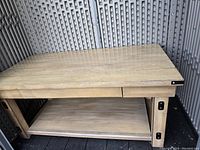 Front perspective of the wooden coffee table showing drawer and lower shelf with metal corner brackets