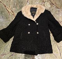Full front view of the black curly lamb fur coat featuring beige mink fur collar and double-breasted button closure.