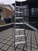Full view of the 8-foot aluminum step ladder in A-frame position on outdoor pavement with residential houses in background.