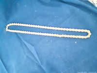 20 inch gold-tone rope chain necklace laid flat on blue fabric.