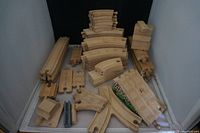 Wide view showing various wooden railway track pieces arranged in groups including curved, straight, switch tracks, and accessory blocks