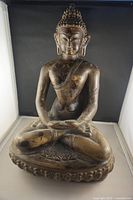Front view of large bronze-style meditating Buddhist statue showing full figure seated cross-legged on decorative base.