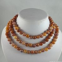 Front view of the multi-strand beaded necklace displayed on a white bust showing color variation and bead finish