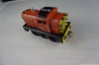 Side angle of Salty cast metal toy train car showing red and black paint with yellow striped detailing.