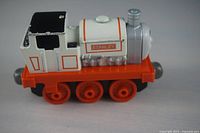 Side view of the Stanley cast metal toy train engine, showing orange wheels, white and black cabin, and silver smokestack.