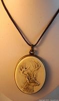 Front view of oval resin deer medallion pendant on black cord necklace.