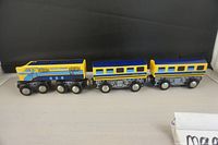 Three piece wooden magnetic train on flat surface with black background shown from side angle