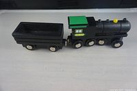 Top and side view of black wooden engine attached to black wooden box car, showing mounted wheels and magnet connectors.