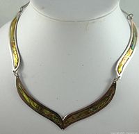 Front view of the green and yellow enamel style metal bib necklace on a display bust.