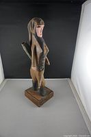 Front left-facing view of the hand-carved female hunter wooden figure on a base, showing detailed painting and bow quiver.