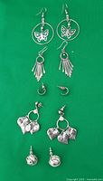 Four pairs of pierced earrings laid out on green background showing all designs and details