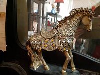 Front and side view of the ornate gold horse figurine showing overall shape and decoration.