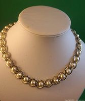 Front view of the faux pearl necklace displayed on a white stand, showing the pearl and silver-tone chain design and the full length view.