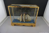 Overall view of the ship model in the rectangular glass display case with wooden base.