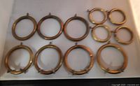 Ten brass rings arranged flat, showing both larger rings with rolling wheels and smaller rings without wheels.