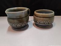 Side view of the vintage Irish porcelain creamer and sugar bowl showing the shamrock pattern around middle and earth-tone glaze