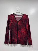Full front view of red snake print blouse with zipper on hanger against white background