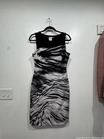 Front view of the sleeveless dress on a hanger showing solid black top and black and white patterned skirt.