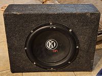 Front view showing the Monster SR black subwoofer in carpeted enclosure.