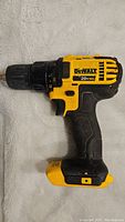 Side view of yellow and black DeWalt 20V Max 1/2 inch driver drill lying on a fabric surface showing general condition and branding.