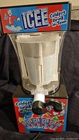 Front view of the Icee Slushie Machine showing the clear plastic container with max fill line, black dispensing handle, and colorful Icee branding with a cartoon character and 'Coldest Drink in Town' text.