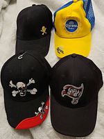 Four assorted new baseball caps including skull themed and Corona Extra trucker style hat.