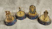 Four Franklin Mint Egyptian statues under glass domes, showing the lot contents.