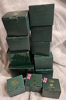Stack of 11 green Harmony Kingdom boxes, showing original packaging and gold lettering.