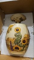 Sunflower and cottage design on a figurine inside a box with foam packing.