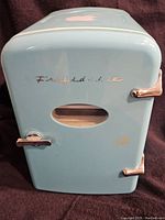 Front view of the light blue mini Frigidaire fridge showing metal handles and small front door display window