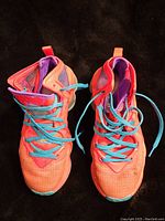 Top-down view of Nike LeBron 19 King's Crown sneakers showing bright coral orange uppers, blue laces, and purple lining.