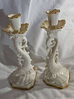 Pair of Lenox Koi Dolphin porcelain candlesticks with white glossy finish and gold trim shown side by side.