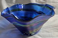 Side view of cobalt blue iridescent glass bowl showing wavy rim and swirl pattern