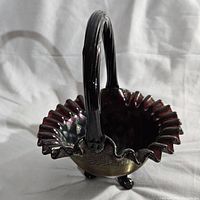 Front and side view of iridescent glass basket showing ruffled edge, deep bowl with intricate pattern, and thick handle.