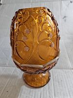 Front angle showing the amber glass fairy lamp with lily of the valley raised floral design and pedestal base.
