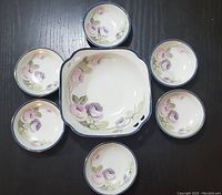 Top view of the set showing large square bowl surrounded by six smaller round bowls, all with matching floral patterns and blue edges.