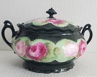 Front side of hand painted MZ Austria biscuit barrel with floral design, showing two handles and lid with finial knob