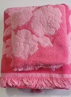 Folded set of towels showing the fringed edges of both towels and visible raised floral pattern on top hand towel.