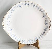 Front view of the Memory Lane by Royal Albert cake plate showing full oval shape, floral edge pattern with blue flowers, and subtle gold trim on handles and rim.