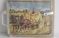 Full view of packaged needlepoint canvas showing horses pulling hay cart with farmers in field and village background. Kit is sealed and unused.