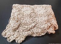Folded view of the vintage handcrafted lace tablecloth showing scalloped floral edge details.