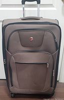 Front view of brown SWISS GEAR suitcase showing telescoping handle extended and front zippered compartments