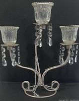 Full view of the three-arm candelabra showing silver tone metal base and arms with glass candle holders and hanging glass prisms