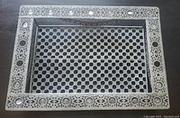 Top view of rectangular silver-tone metal serving tray showing lattice center and ornate border with faux jewels.