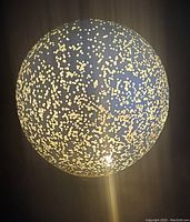 Close-up image of the illuminated glass globe accent light showing the speckled pattern of light dots on its surface.