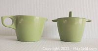 Front view of green melamine creamer and sugar bowl with lid on white background