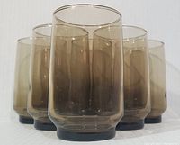 Six smokey brown cylindrical beverage glasses grouped together showing shape,height and color.